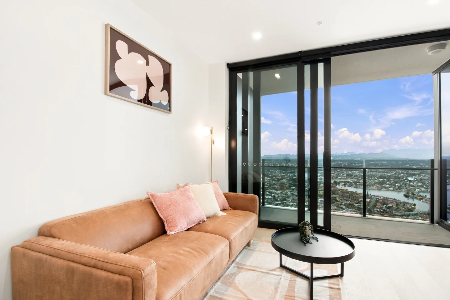 Original photograph of a styled apartment living room with caramel sofa and river views